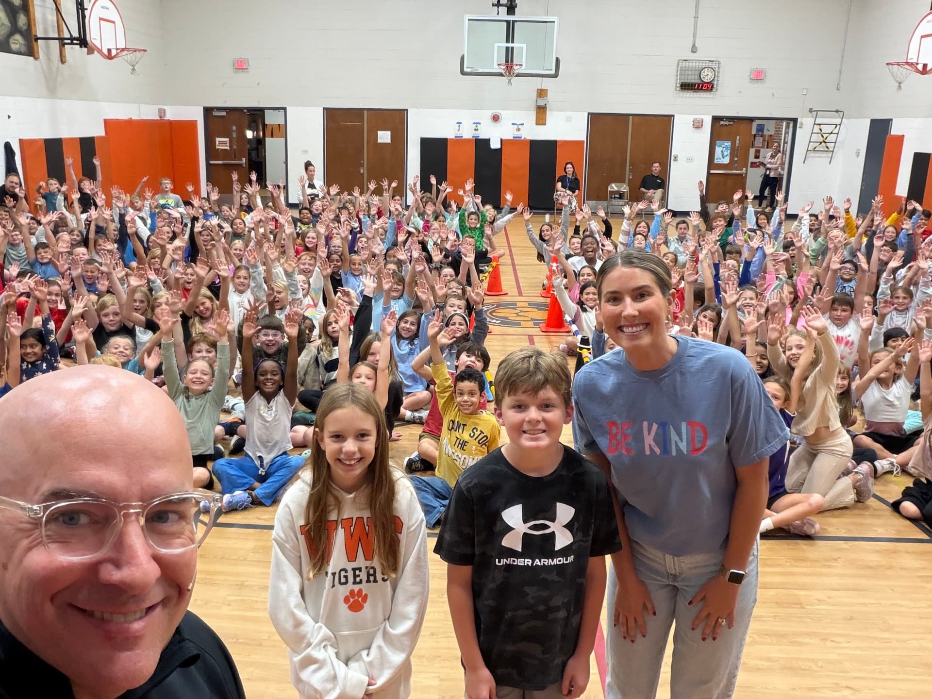 Wiesbrook students wearing Be Kind shirts with their hands in the air